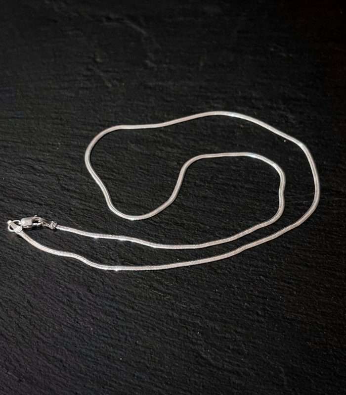 Cadena de plata para collar en acabado brillante sobre fondo oscuro.